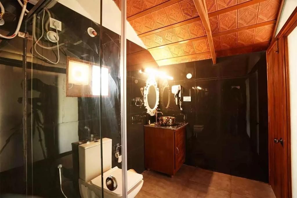Ein Badezimmer mit Duschkabine aus Glas, einem Holzwaschtisch mit Spiegel und einer Toilette.