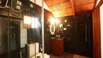 Ein Badezimmer mit Duschkabine aus Glas, einem Holzwaschtisch mit Spiegel und einer Toilette.