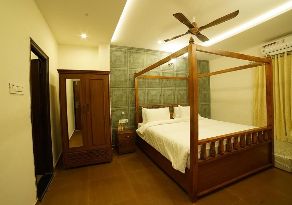 Ein Hotelzimmer mit einem Himmelsbett, Deckenventilator, Kleiderschrank und Spiegel.