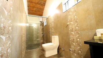 A bathroom with a toilet, shower, and a sink.
