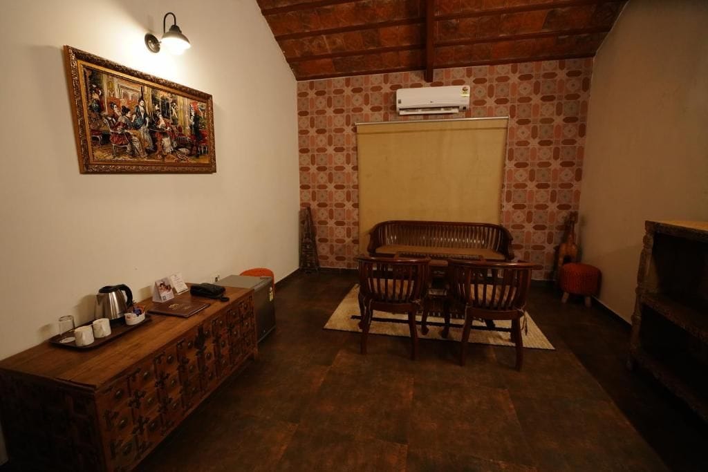 A room with a wooden table, chairs, a painting on the wall, and an air conditioning unit.