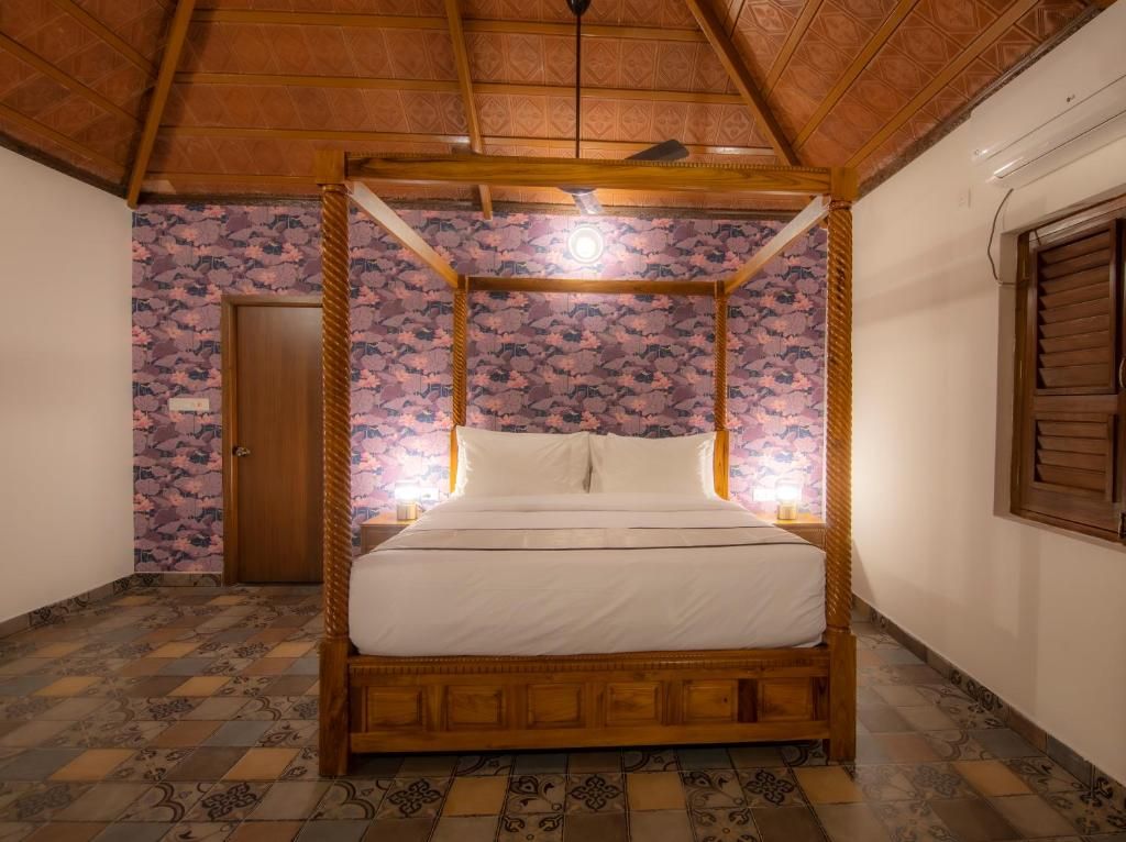 Uma cama com dossel em um quarto com papel de parede estampado e piso de azulejos.