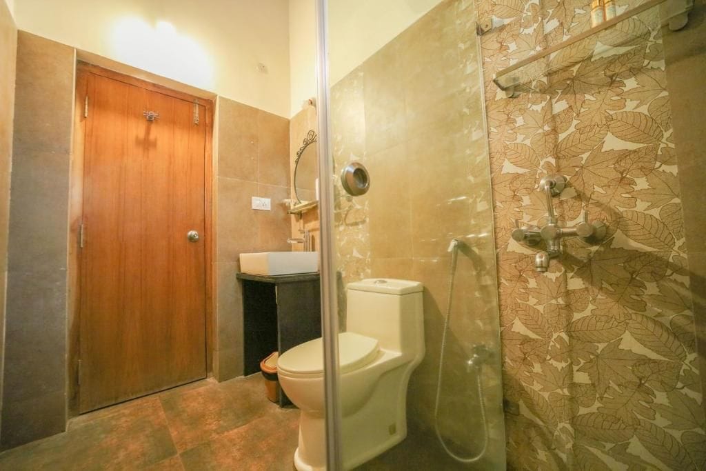 Ein Badezimmer mit Holztür, Toilette, Duschkabine und Waschbecken.