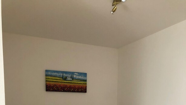 A hotel room with two beds, a nightstand, a lamp, and a painting on the wall.