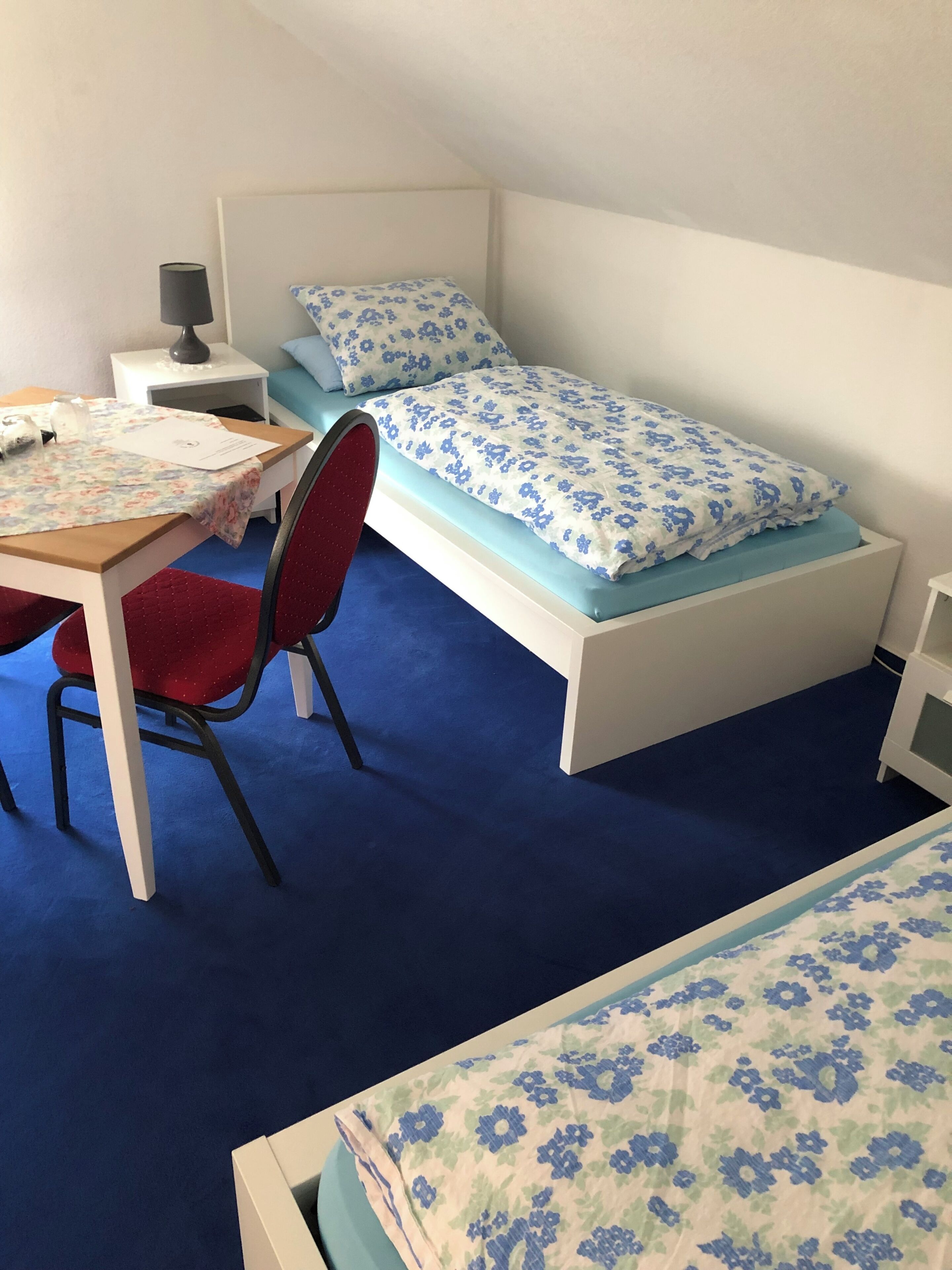 Ein kleines Zimmer mit einem Bett, einem Schreibtisch und einem Stuhl.