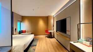Una habitación de hotel moderna con cama, escritorio, silla, televisor y minibar.