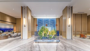 Un vestíbulo moderno con un mostrador de recepción de mármol, zona de estar y un arreglo floral central.