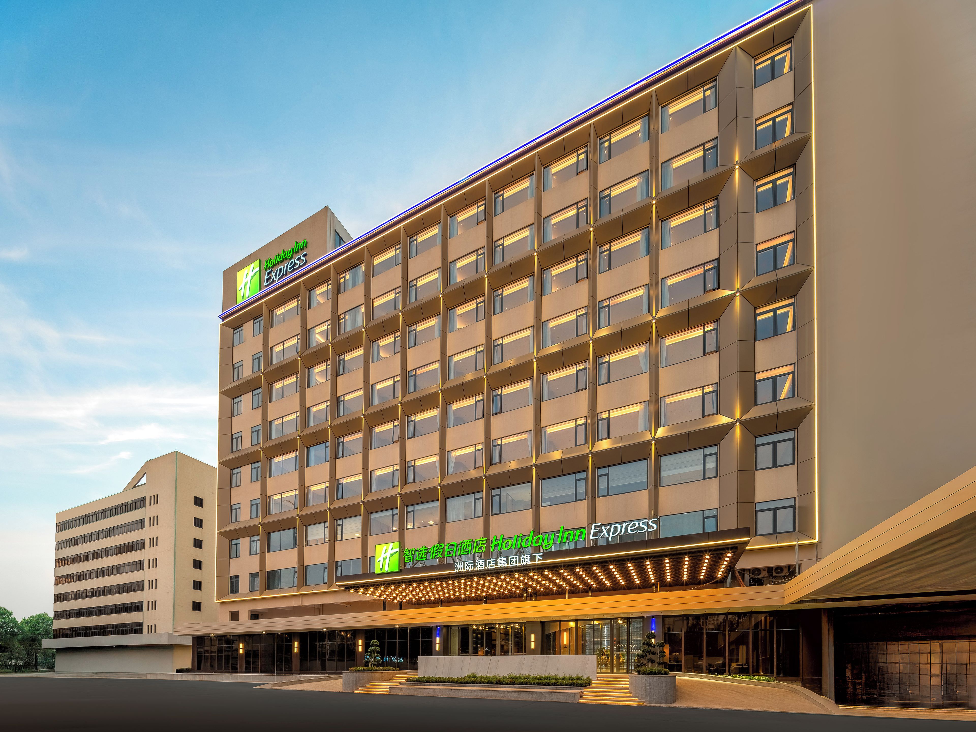 A Holiday Inn Express hotel with a modern design, featuring multiple floors and a prominent entrance with illuminated signage.