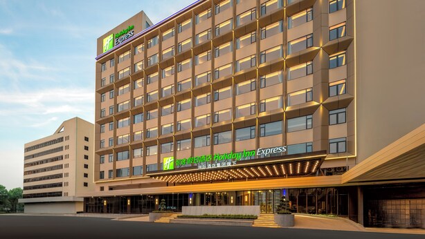 Un hotel Holiday Inn Express con un diseño moderno, que cuenta con varios pisos y una entrada destacada con señalización iluminada.