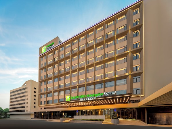 Un hotel Holiday Inn Express con un diseño moderno, que cuenta con varios pisos y una entrada destacada con señalización iluminada.