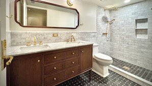 A bathroom with a marble vanity, a toilet, and a shower with a brick wall backdrop. - Mapleton Hill Guest Suite in Boulder Historic District - few steps from Pearl St (Boulder)