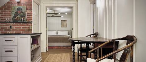Una habitación con una mesa de comedor, sillas, una cama y una pared de ladrillo con un cuadro.