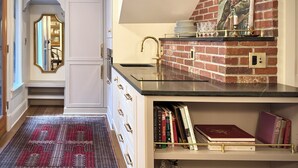 A kitchen with a brick accent wall, a black countertop, and a built-in bookshelf with cookbooks. - Mapleton Hill Guest Suite in Boulder Historic District - few steps from Pearl St (Boulder)