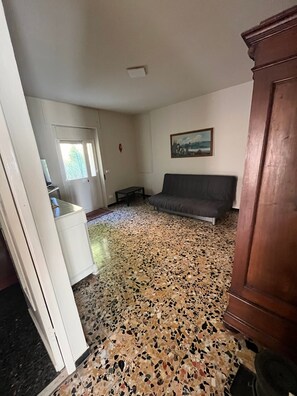 Ein Zimmer mit einer Couch, einem Schrank, einem Bild an der Wand und einem gemusterten Boden.