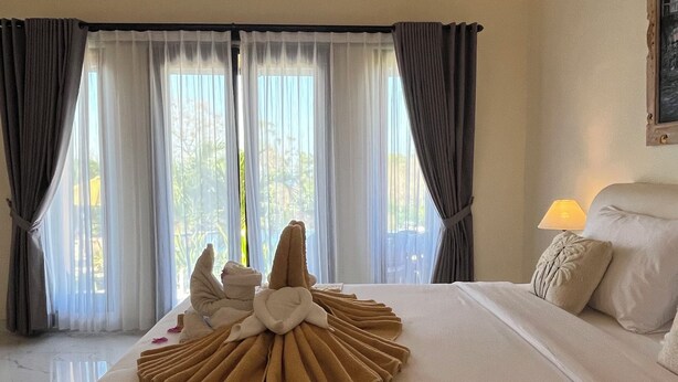 Una habitación de hotel con una cama grande, una decoración de toallas y vistas por la ventana.