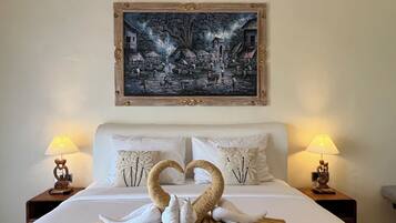 Une chambre d’hôtel avec un lit, deux tables de chevet, un tableau au-dessus du lit et une présentation originale des serviettes.