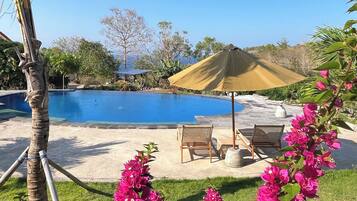 A clear blue sky, a swimming pool, and a grassy area with chairs and a table.