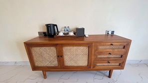 Un mueble de madera con cafetera, botellas y una caja de pañuelos.
