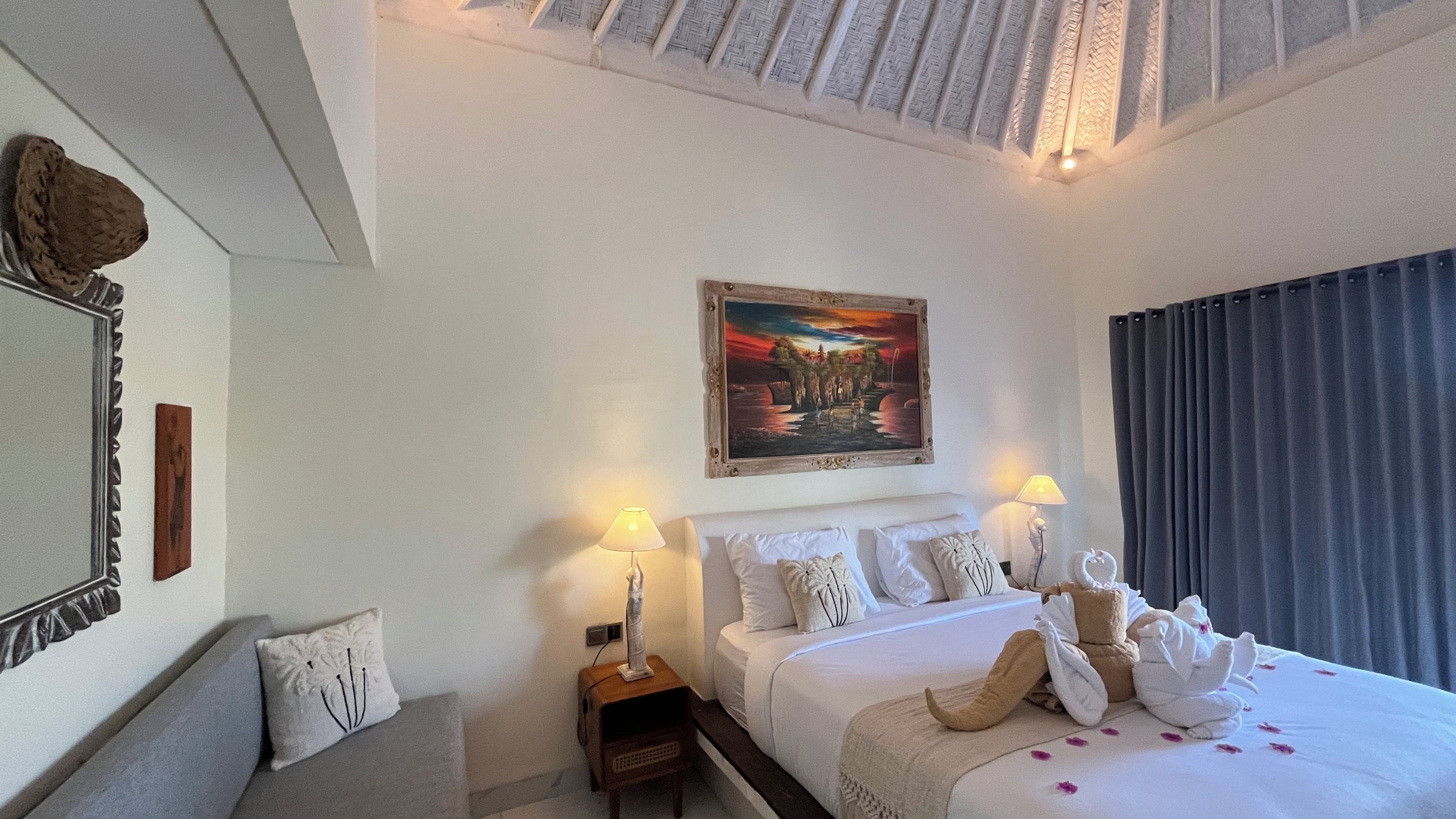 Een hotelkamer met een bed, twee bedlampen, een schilderij en een raam met gordijnen.