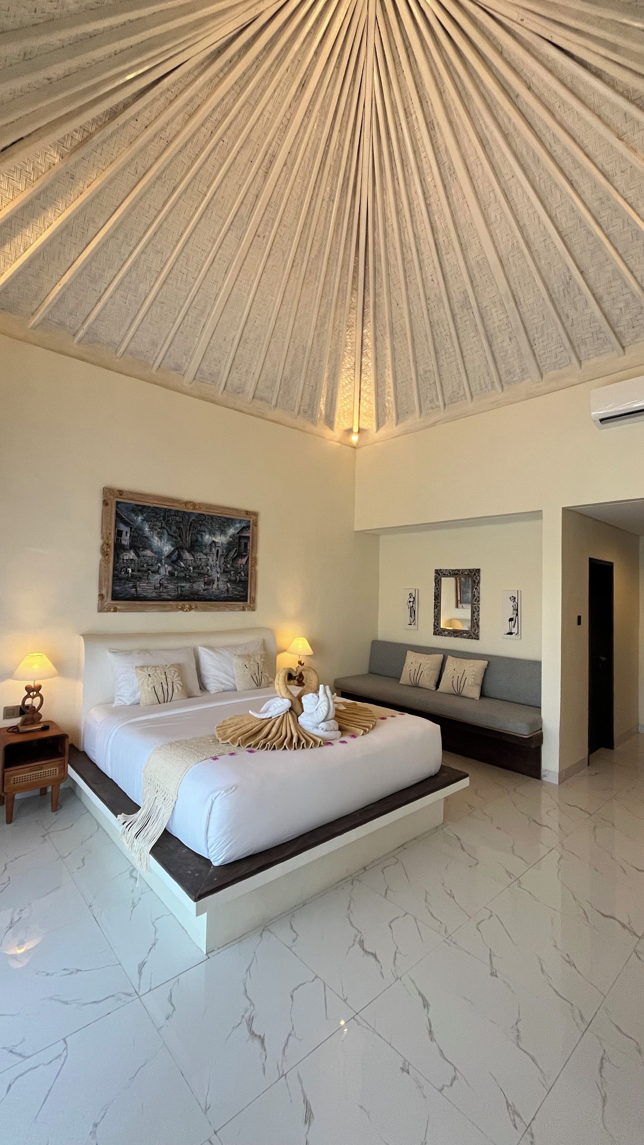 Quarto moderno com cama grande, sofá e teto com design radial.