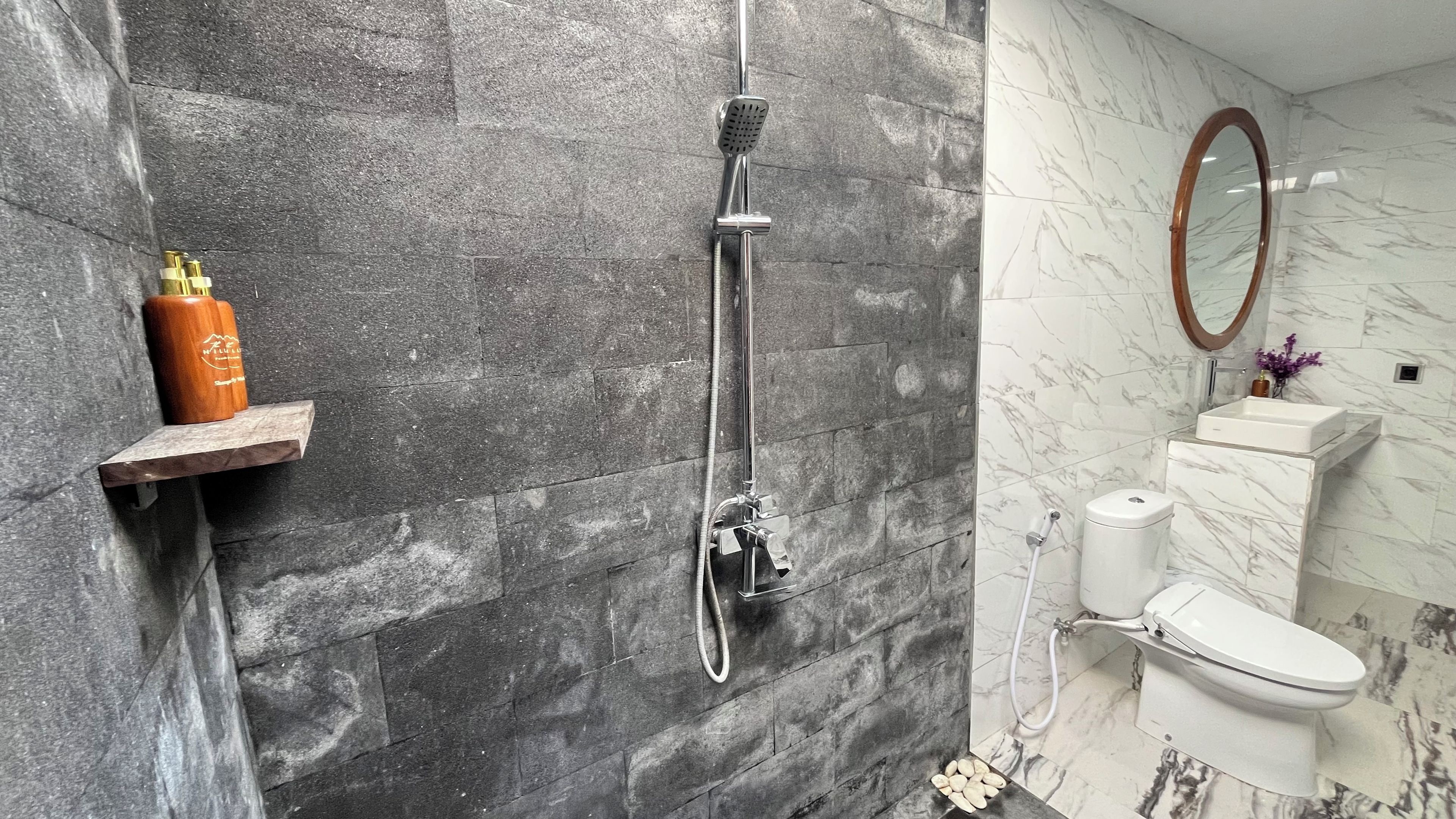 A bathroom with a shower, toilet, and marble walls.