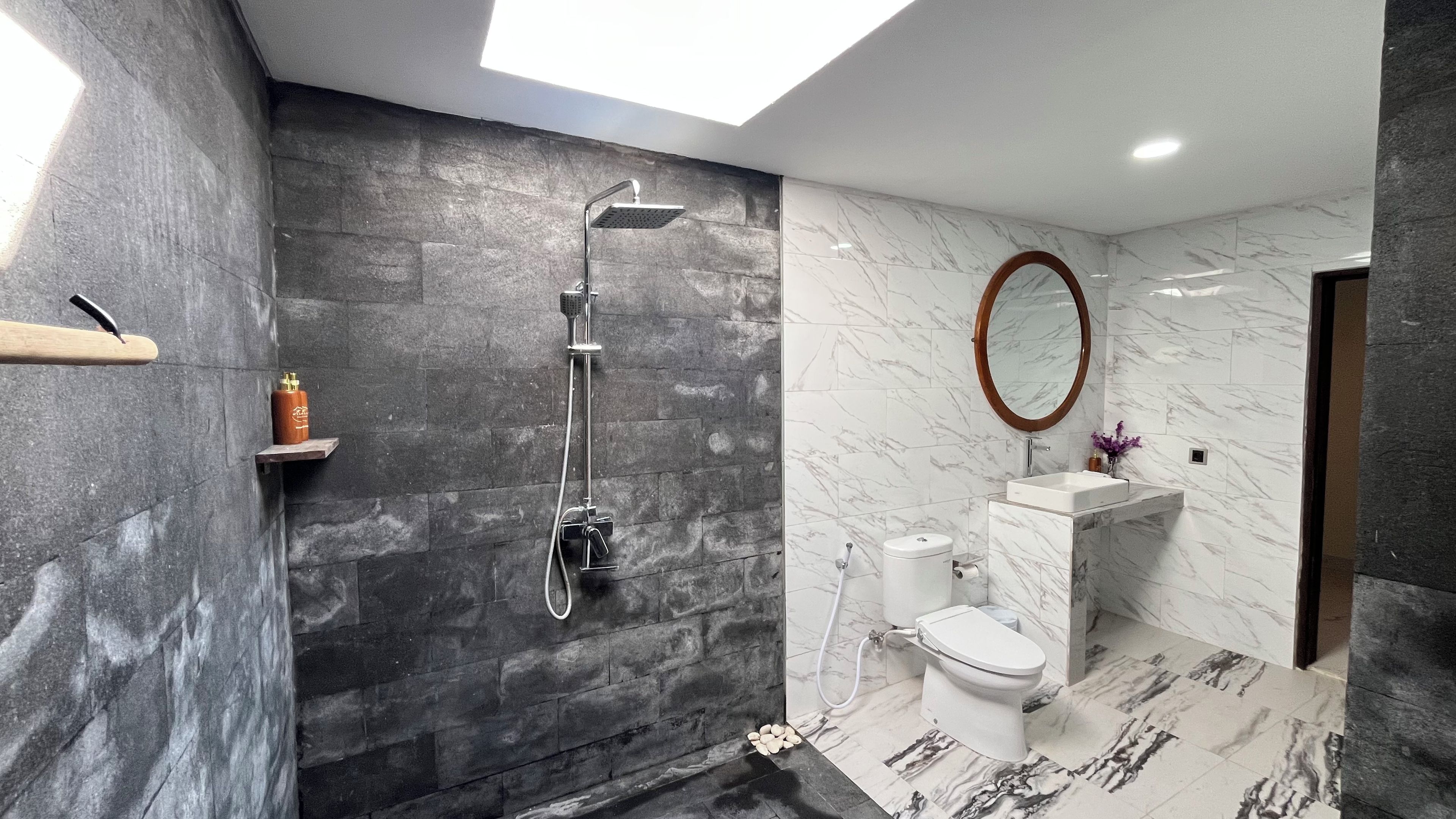 Een moderne badkamer met douche, toilet en wastafel.