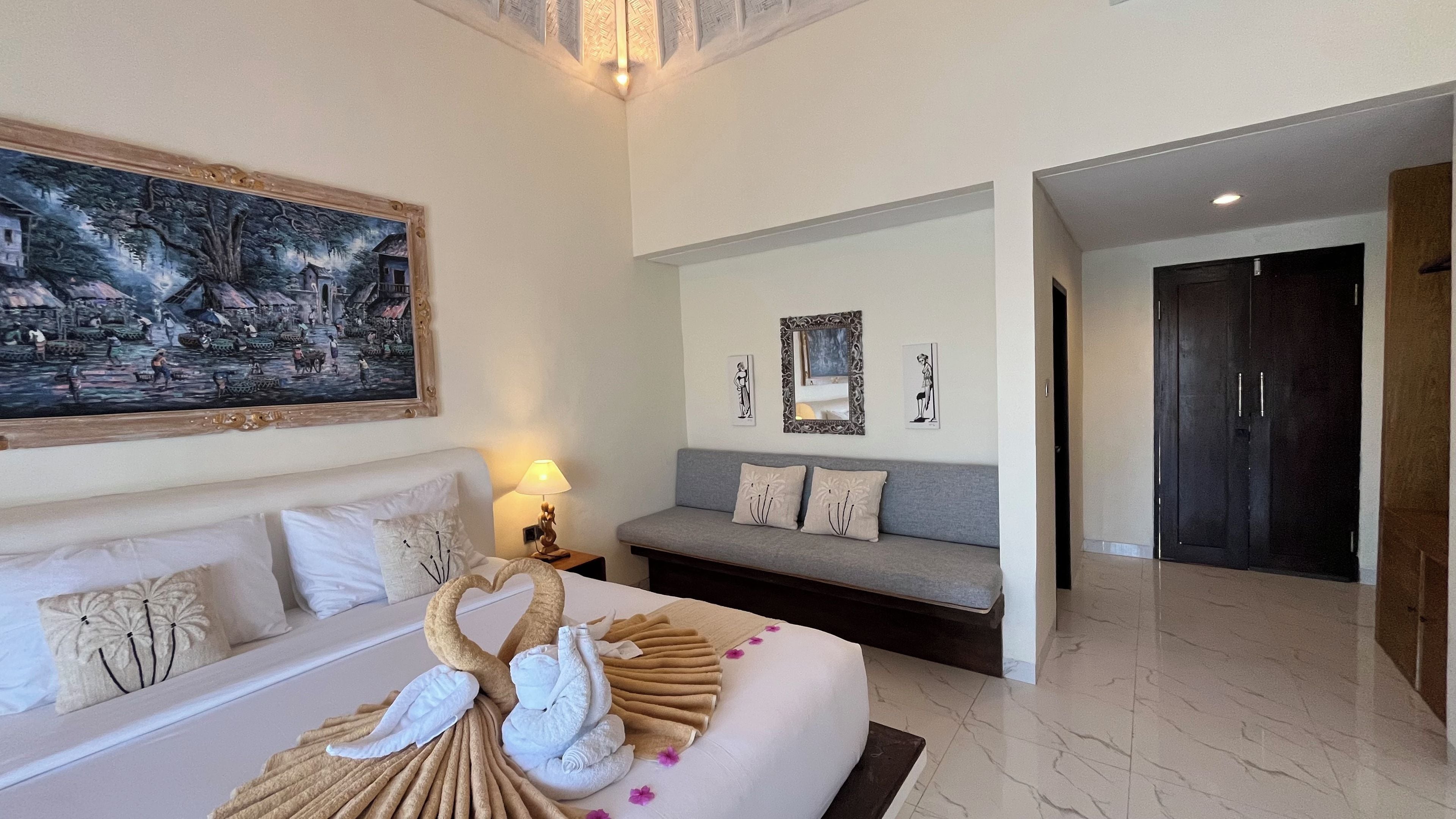 Une chambre d’hôtel avec un grand lit, un canapé, un tableau et un miroir.