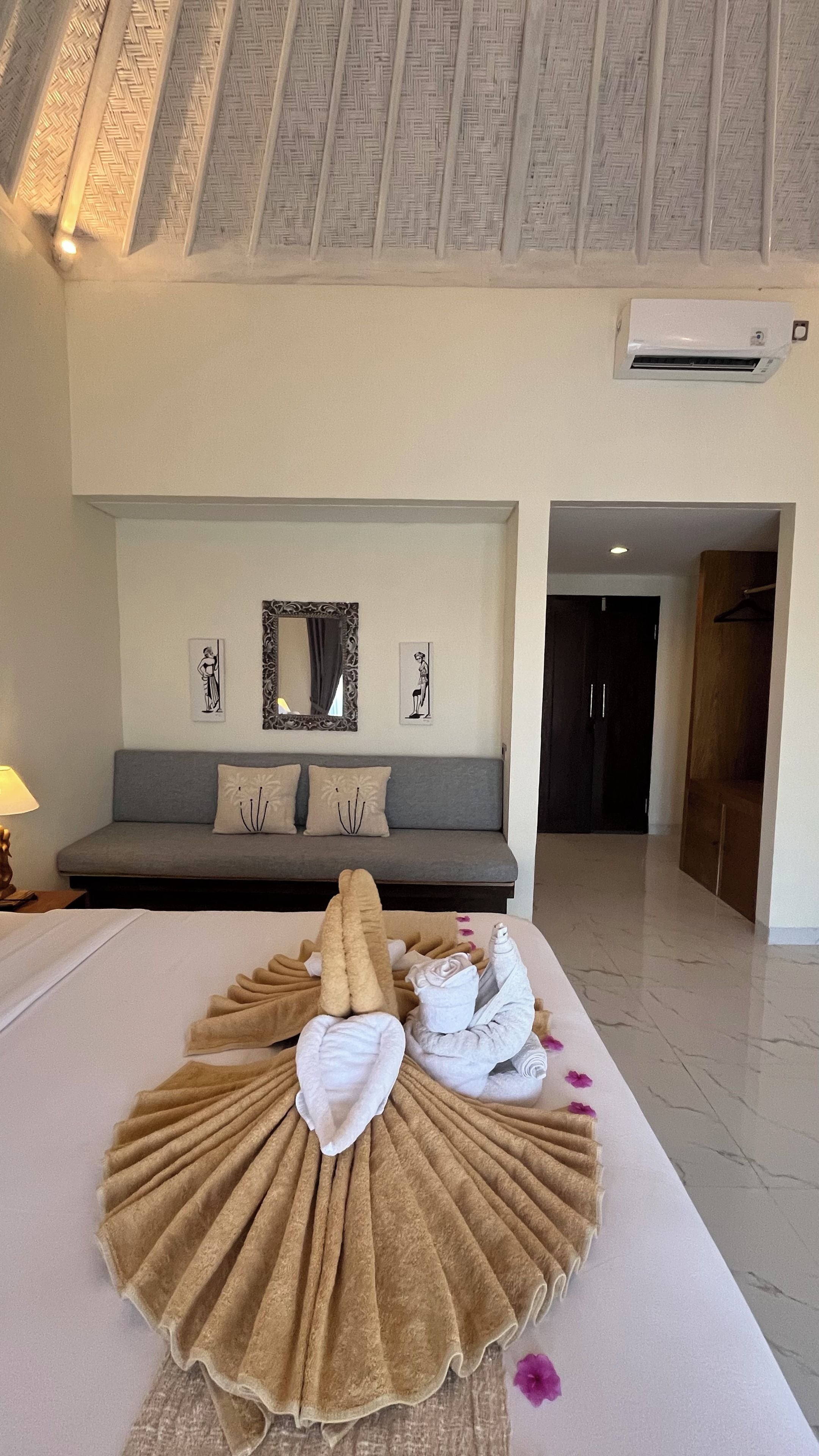 Een hotelkamer met een bed, een bank, een spiegel en een airconditioning.