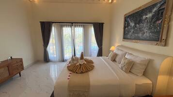 Habitación de hotel con una cama grande, un cuadro en la pared y vistas al exterior a través de las ventanas.
