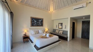 A hotel room with a large bed, a sofa, a painting, and a mirror.