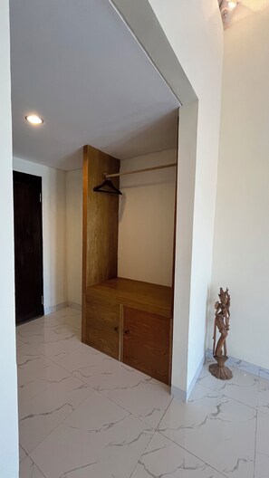 A room with a wooden bench, a coat rack, and a statue. - The Hills Penida (Klungkung)
