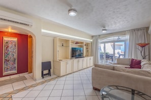 A living room with a television, sofa, and a glass coffee table. - Oceanview Retreat in Amapas at Estrellita del Mar 2BD Condo for rent in Amapas, (Puerto Vallarta)