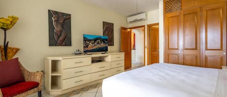 Ein Schlafzimmer mit einem Bett, einem Fernseher auf einer Kommode und Kunstwerken an der Wand.