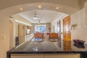 A hotel lobby with a marble reception desk, two chairs, a ceiling fan, and a view of the outside. - Oceanview Retreat in Amapas at Estrellita del Mar 2BD Condo for rent in Amapas, (Puerto Vallarta)