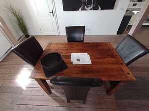 A dining table with four chairs, a black basket, and a piece of paper on the table. - Speicherstübchen (Schönberg)