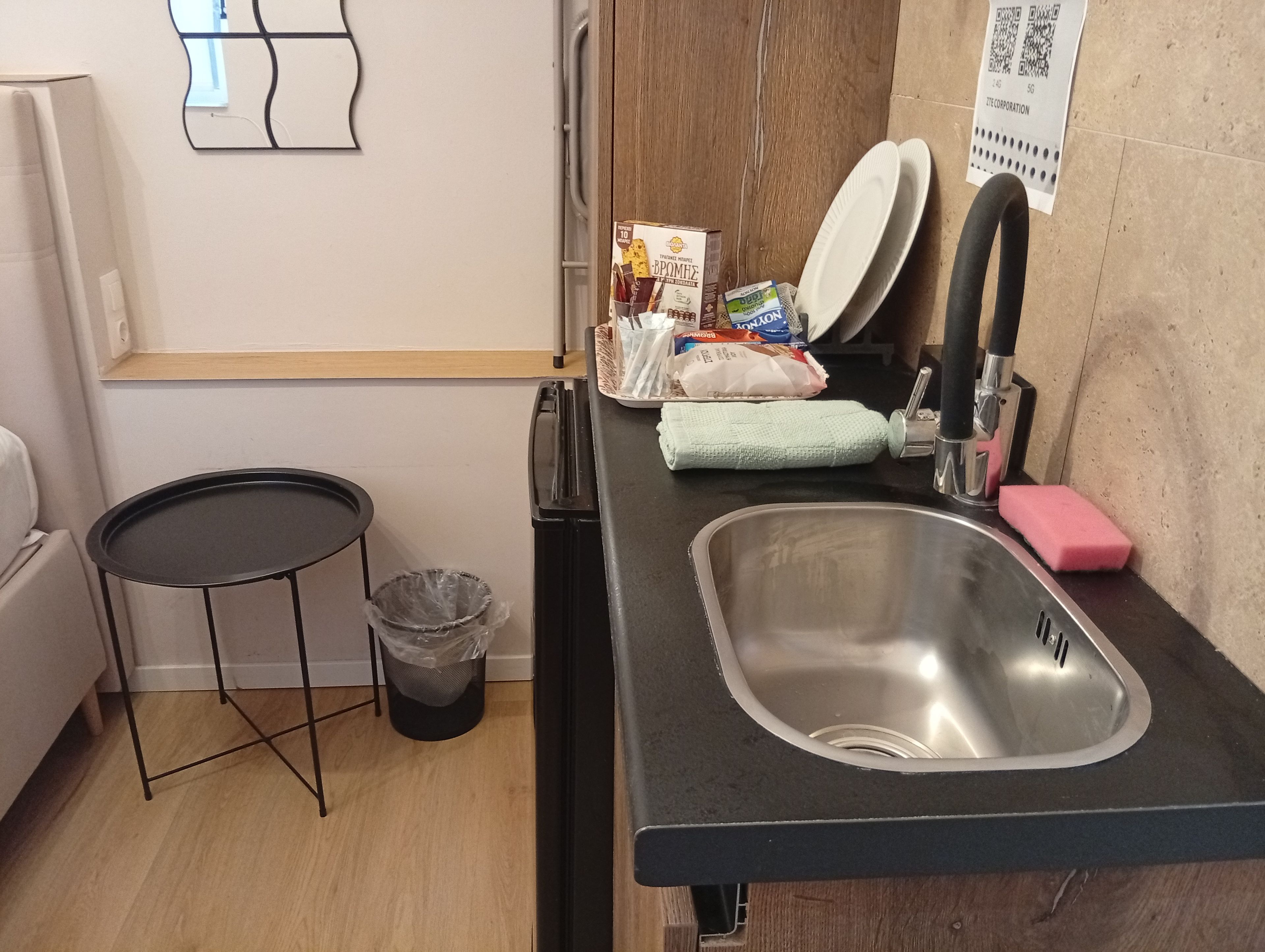 Cocina compacta con un lavamanos, un cesto de basura pequeño y una mesa redonda.