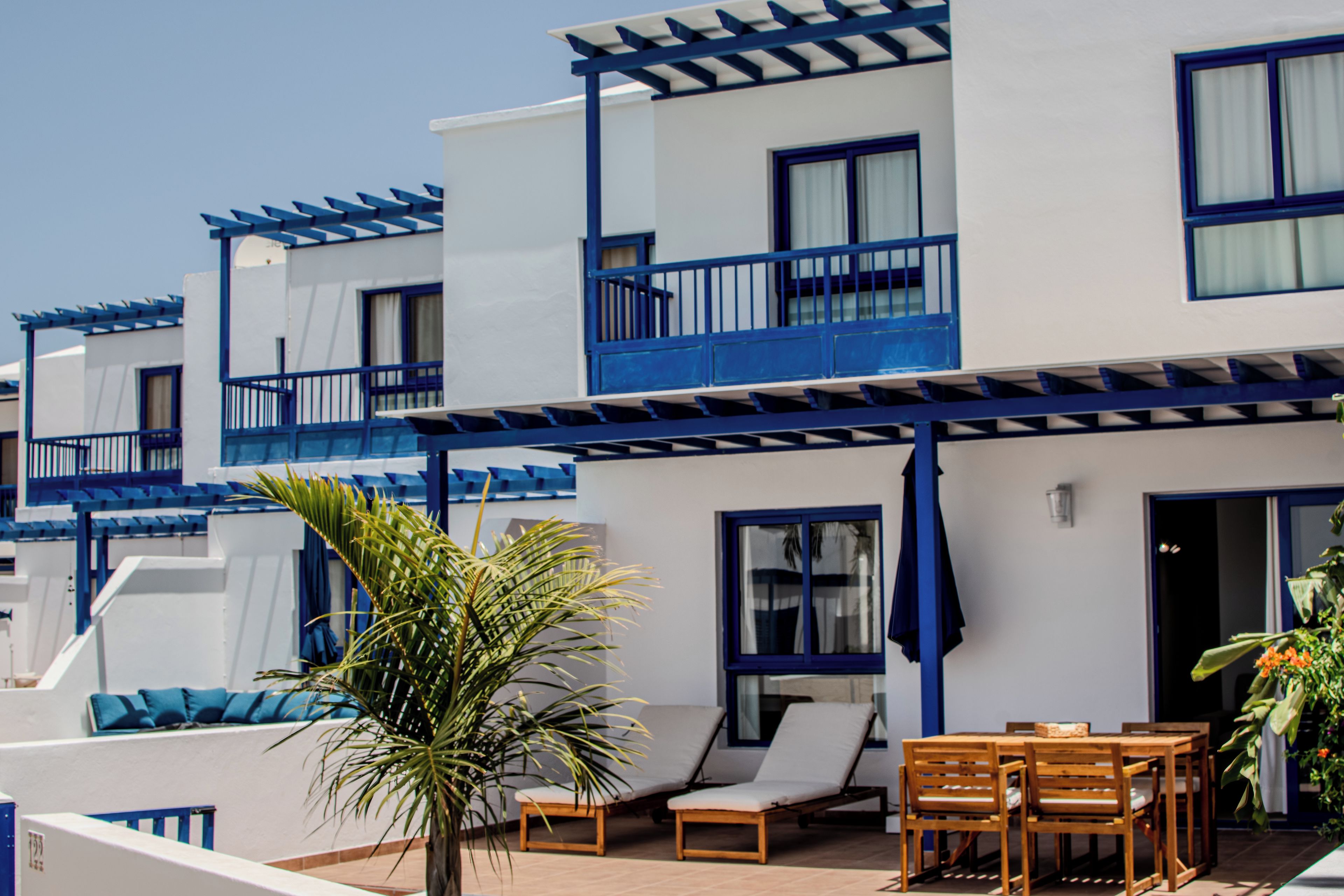 A hotel with multiple balconies, outdoor seating, and a palm tree.