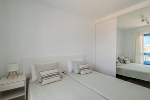 Une chambre d’hôtel avec un lit, une table de chevet, une lampe et un miroir.
