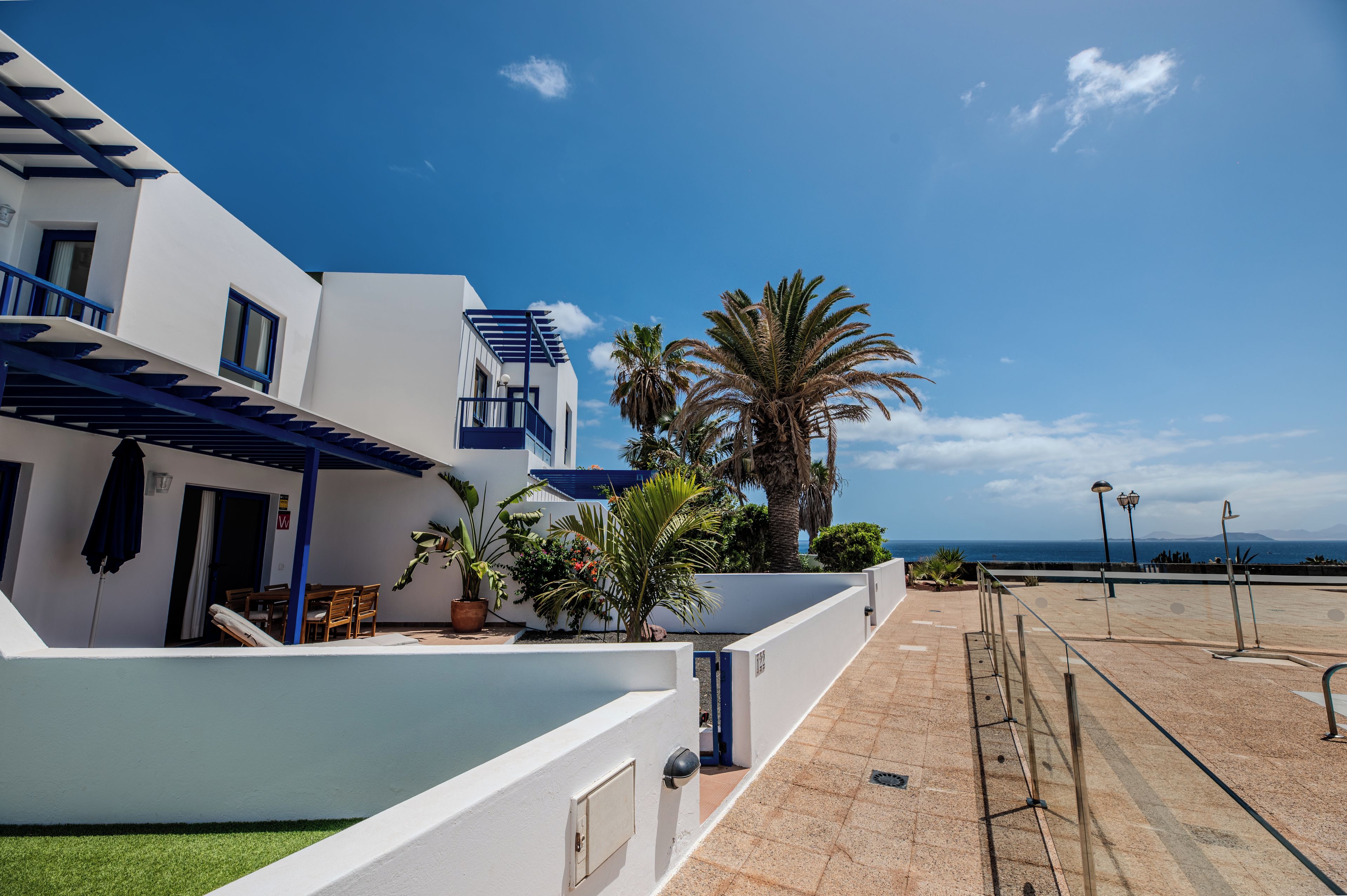 A modern building with a pool, outdoor seating, and a view of the sea.
