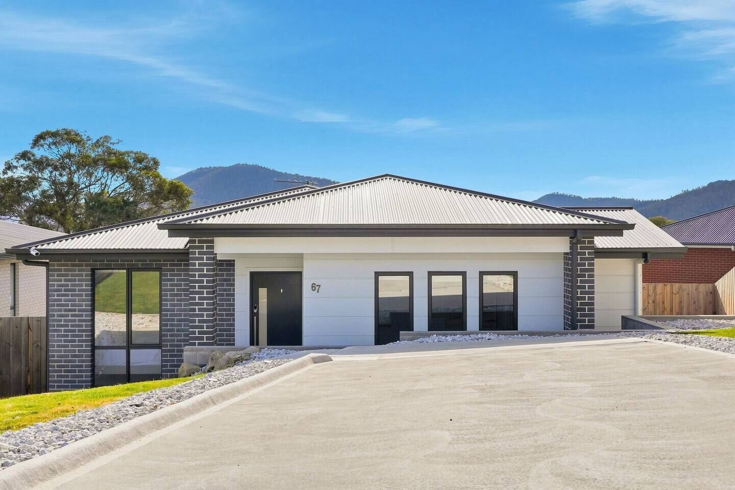 Una casa moderna a un piano con garage, ampie finestre e vialetto.
