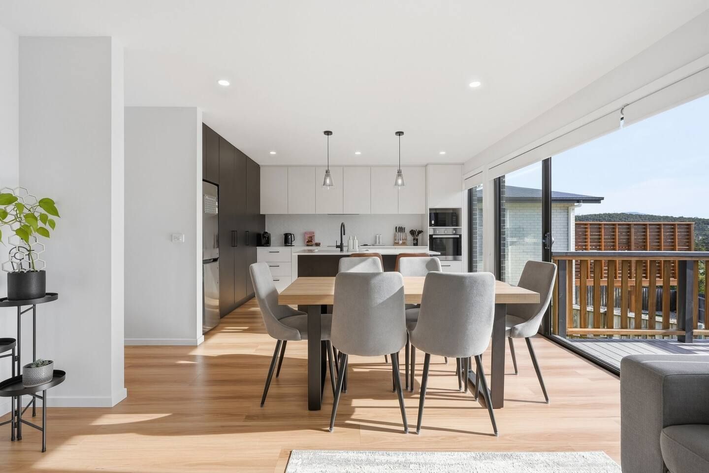 A modern kitchen with a dining area, large windows, and a balcony.