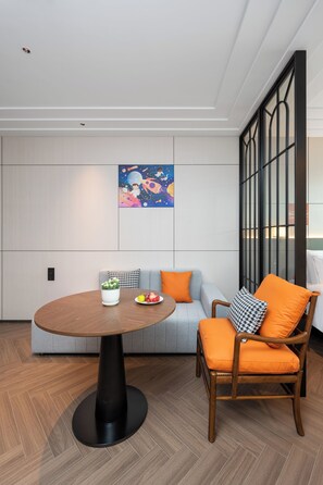 A modern interior with a round table, a sofa, and a chair with orange cushions.