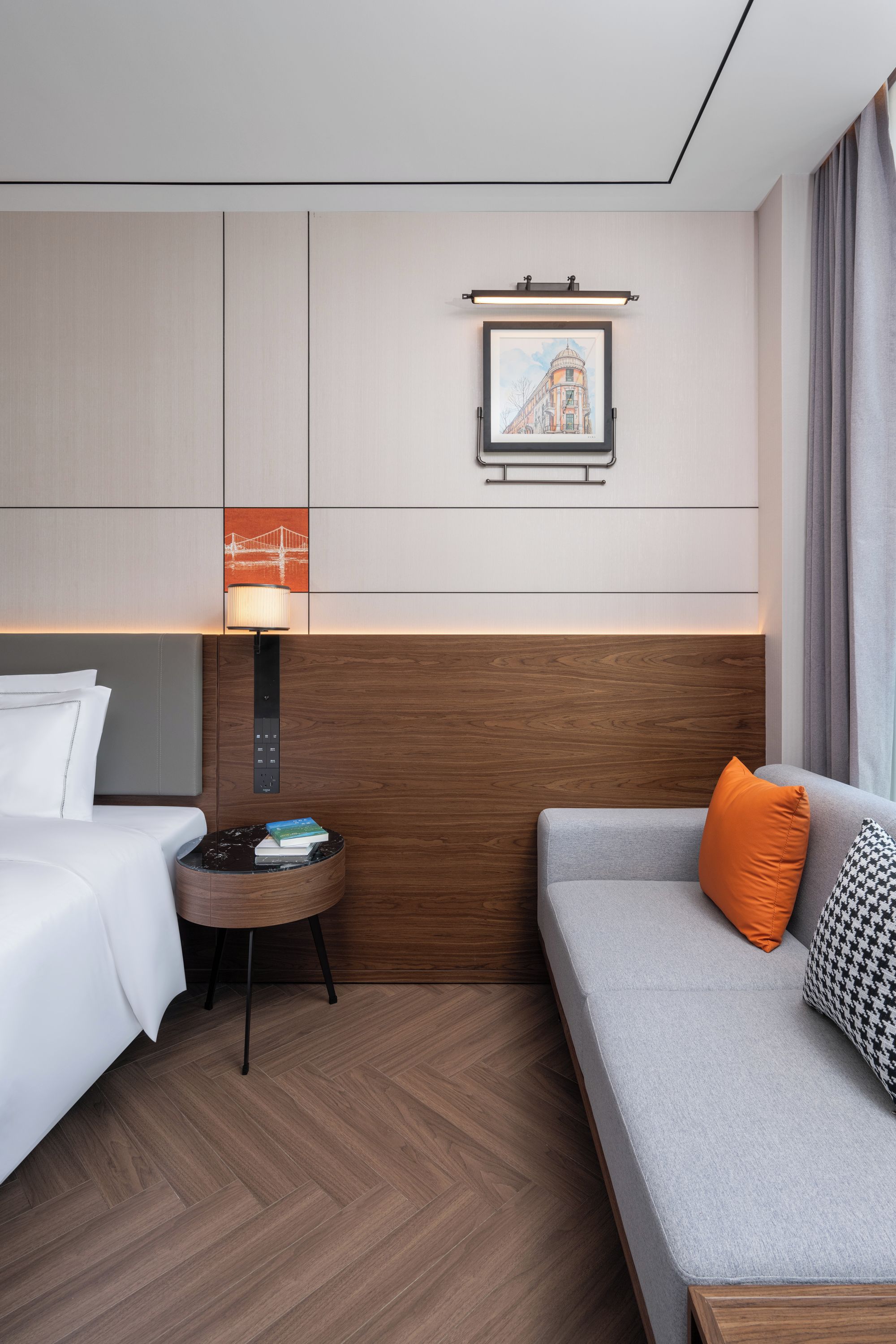 Una habitación de hotel con cama, sofá, una mesita con lámpara y un cuadro colgado en la pared.