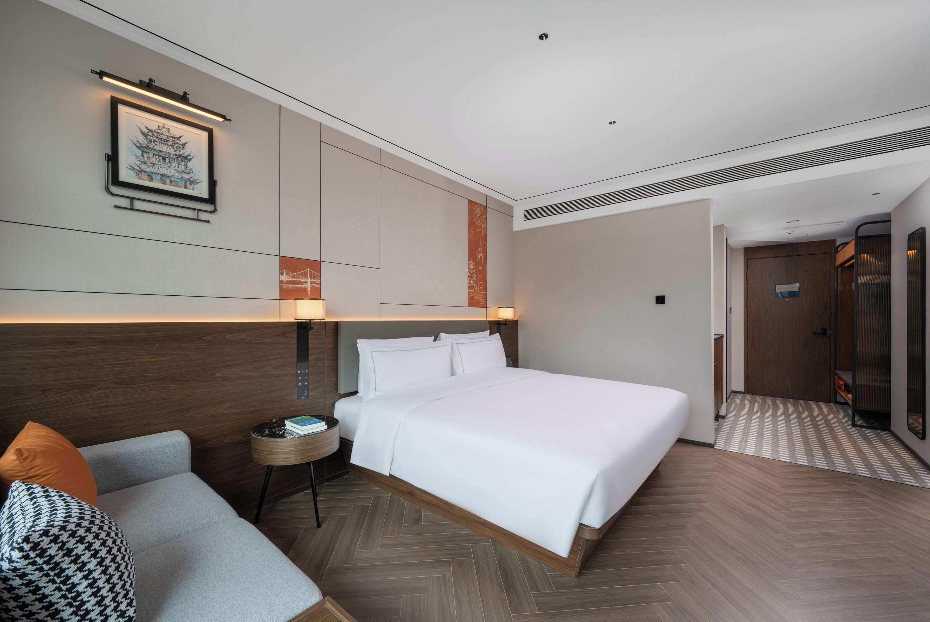 Habitación de hotel con una cama grande, una mesita de noche pequeña, una silla y una obra de arte colgada en la pared.