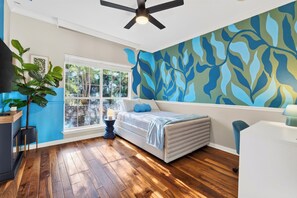 A bedroom with a large window, a ceiling fan, and a wall with a leafy pattern. - ACL Weekend | Sleeps 22 | Pool + Hot Tub + Sauna | Game Room | The Reset Estate (Austin)