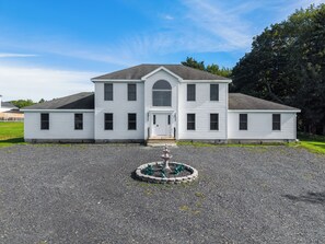 A two-story white building with a central entrance and a circular garden feature in front. - NEW! Indoor Lounge Pool Hot tub Glamping Karaoke (Tobyhanna)