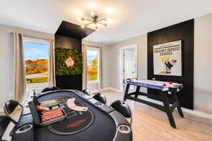 A room with a foosball table, a pool table, and a wall-mounted poster. - NEW! Indoor Lounge Pool Hot tub Glamping Karaoke (Tobyhanna)