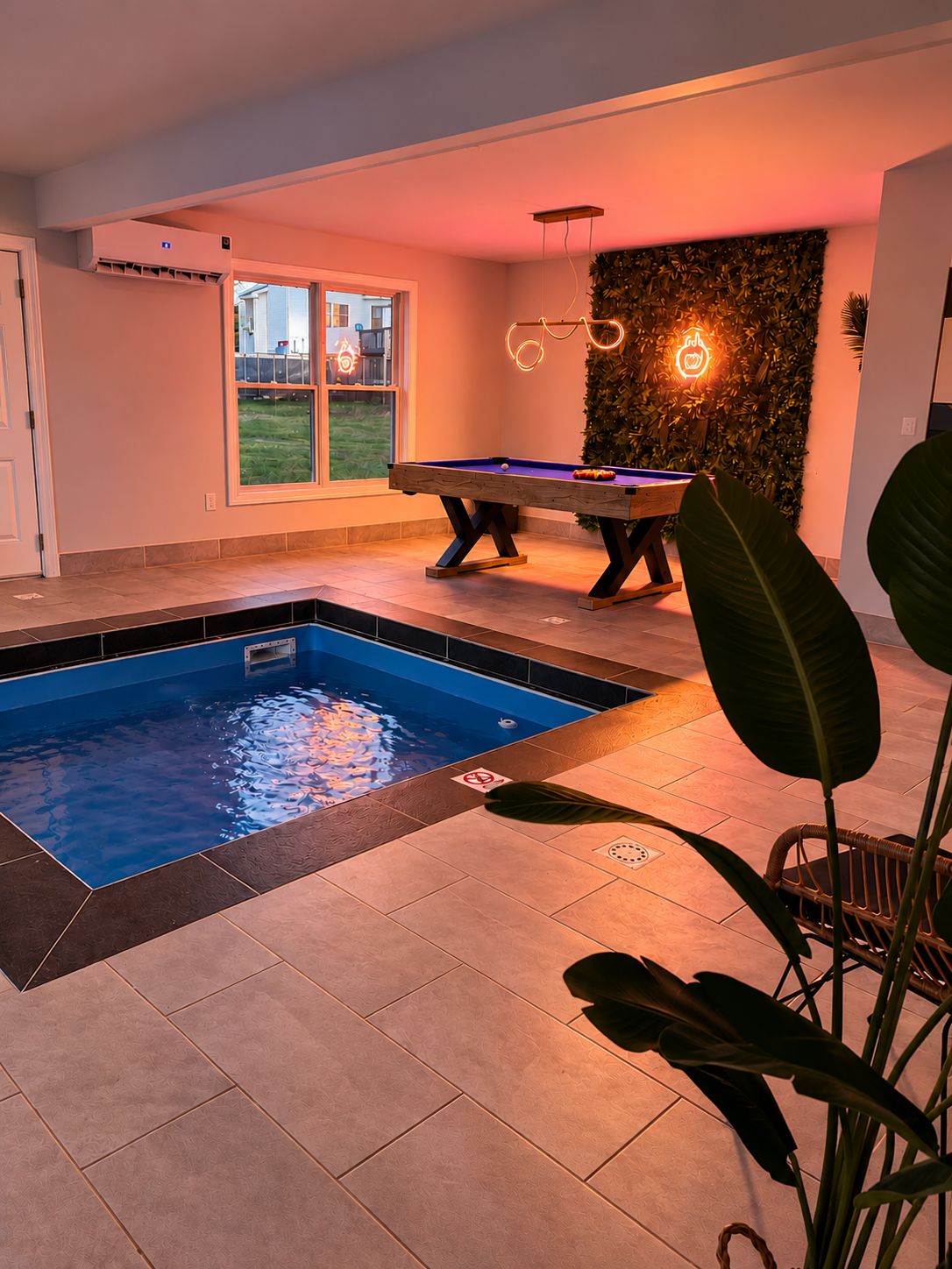 Une piscine intérieure avec une table de billard et un panneau lumineux au fond.