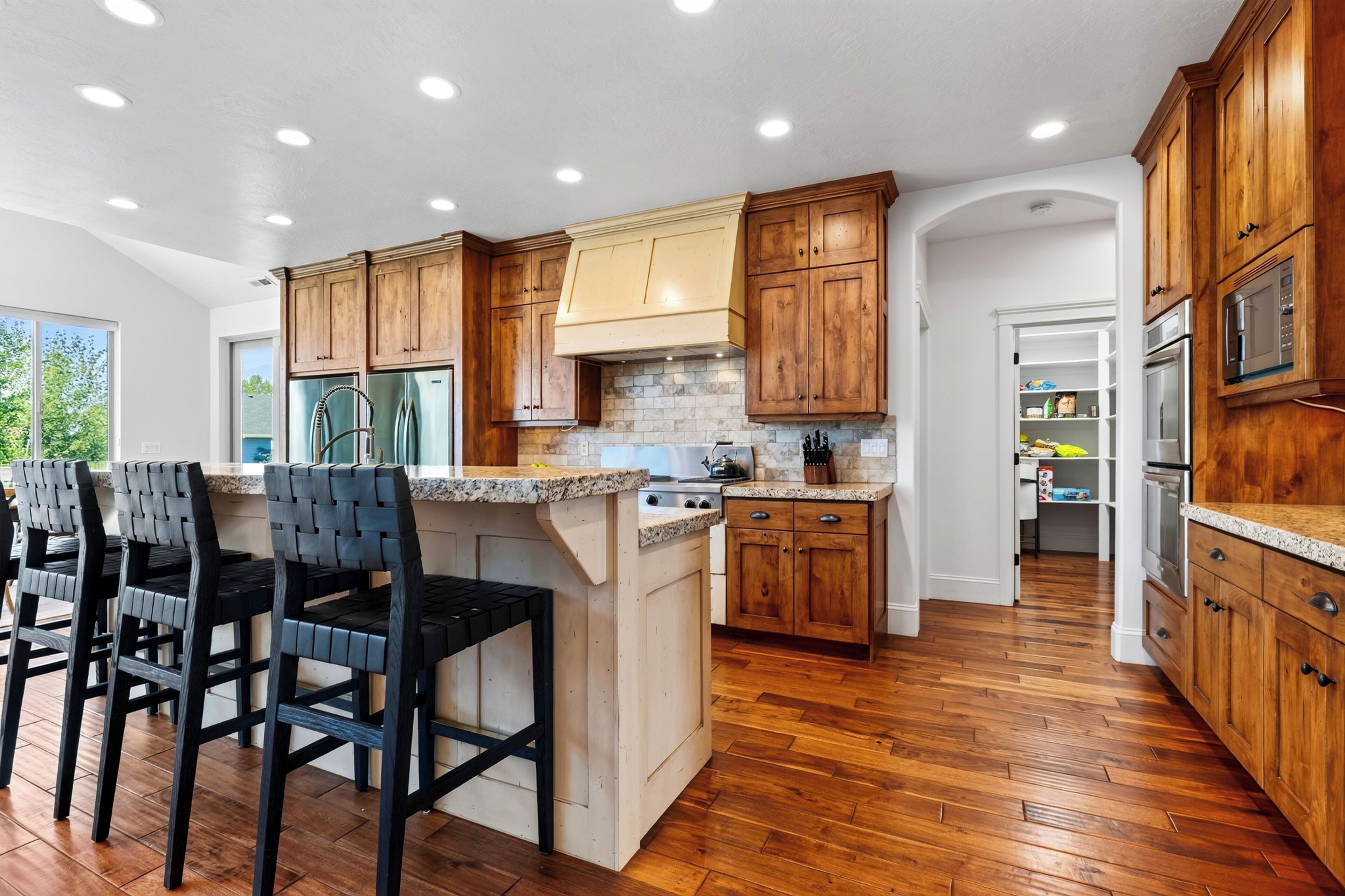 A modern kitchen with wooden cabinets, a granite countertop, and a built-in island with bar stools.