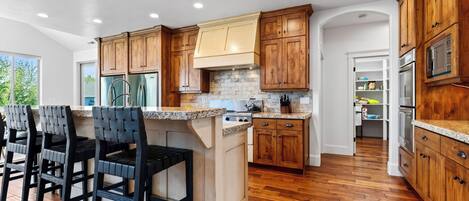 A modern kitchen with wooden cabinets, a granite countertop, and a built-in island with bar stools.